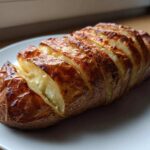 A perfectly cooked air fryer baked potato, sliced thinly like an accordion, with a crispy, golden-brown skin.