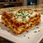 A perfect, thick slice of amazing 3 layer lasagna featuring rich meat sauce, creamy ricotta, and melted mozzarella topping.