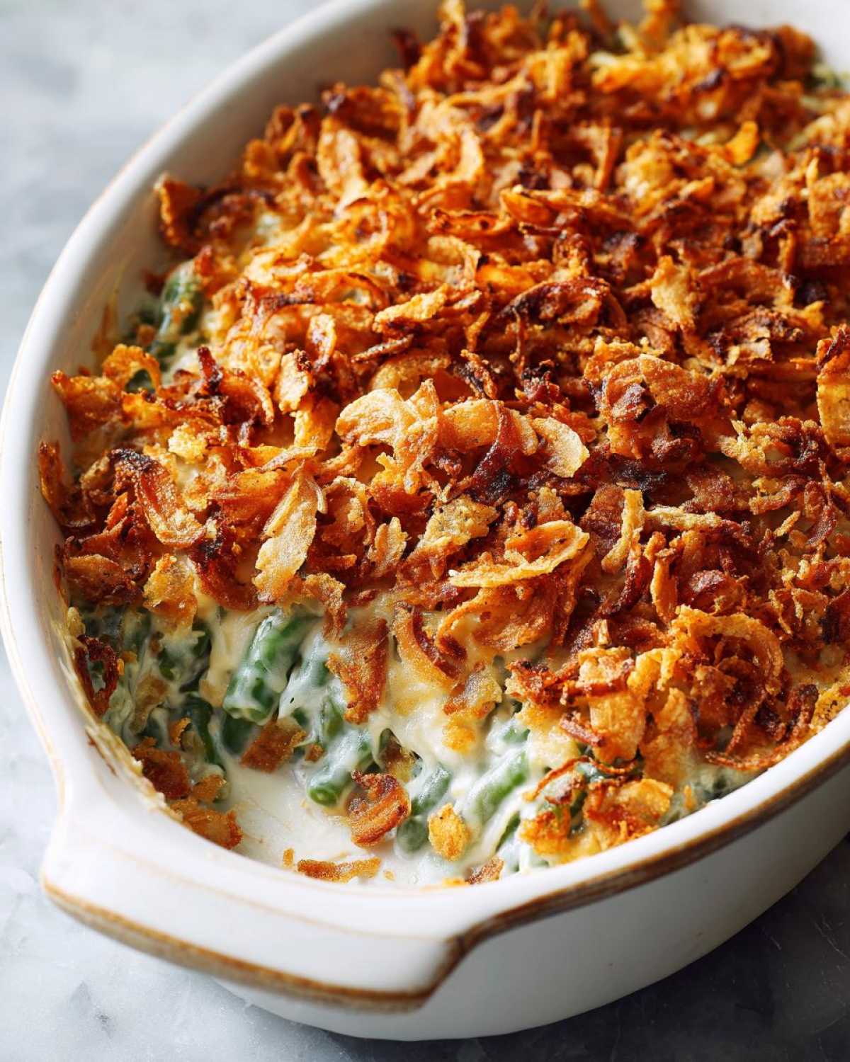 Close-up of a creamy green bean casserole topped generously with crispy fried onions.