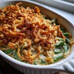 A close-up of a creamy green bean casserole topped generously with crispy fried onions, ready to serve.