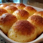 Close-up of freshly baked, soft dinner rolls glistening with butter and topped with cinnamon sugar.