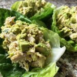 Close-up of creamy avocado chicken salad served in fresh, vibrant green lettuce cups.
