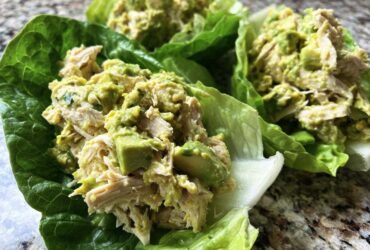 Close-up of creamy avocado chicken salad served in fresh, vibrant green lettuce cups.