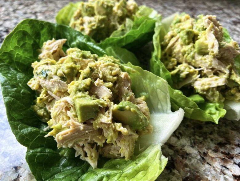 Close-up of creamy avocado chicken salad served in fresh, vibrant green lettuce cups.