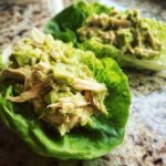 Close-up of creamy avocado chicken salad served in bright green butter lettuce cups.