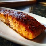 Close-up of a perfectly baked salmon fillet with a shiny, dark glaze and visible spices.