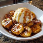 Close-up of Bananas Foster: caramelized banana slices topped with vanilla ice cream and brown sugar.