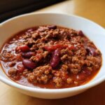 Close-up of a rich, thick bowl of chili featuring ground beef and kidney beans, showcasing the best chili recipe.
