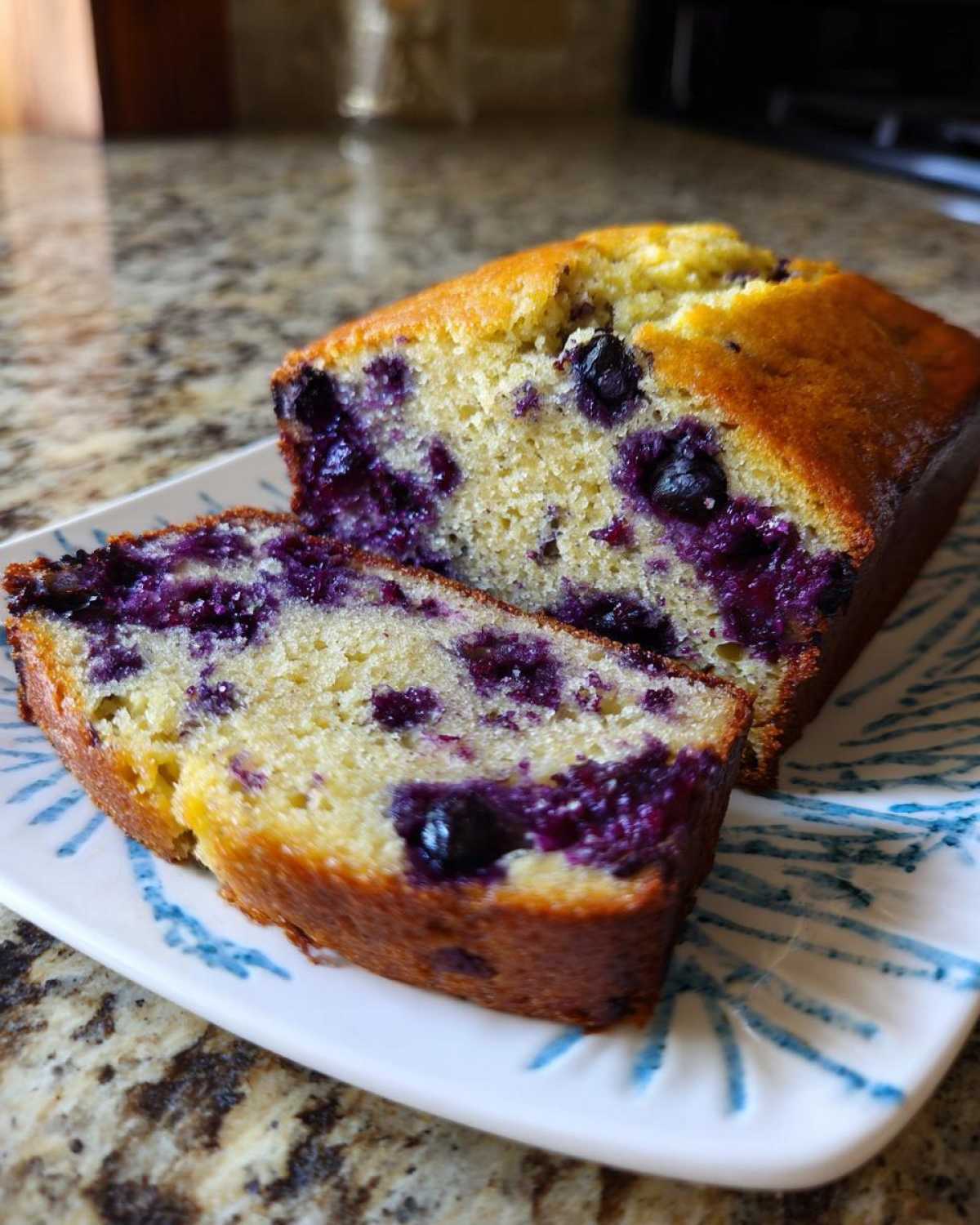 A close-up of sliced blueberry banana bread showing moist crumb and bright purple blueberries.