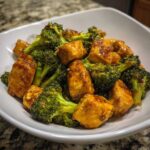 Close-up of tender chicken and bright green broccoli florets coated in a savory brown sauce, highlighting the chicken and broccoli.