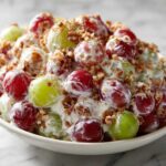Close-up of creamy grape salad with red and green grapes, topped with chopped pecans, resembling chicken salad chick grape salad.