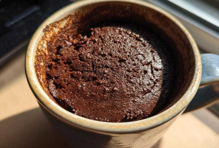 Close-up overhead shot of a rich, dark chocolate mug cake freshly baked inside a rustic ceramic mug.