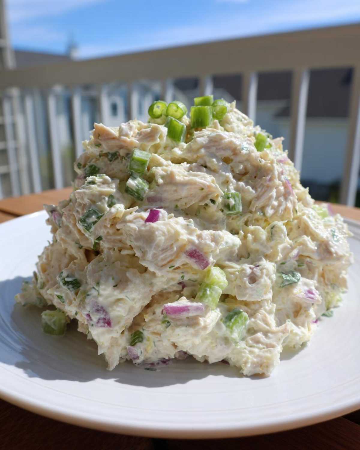 A mound of creamy cottage cheese chicken salad mixed with celery and red onion, topped with green onions.