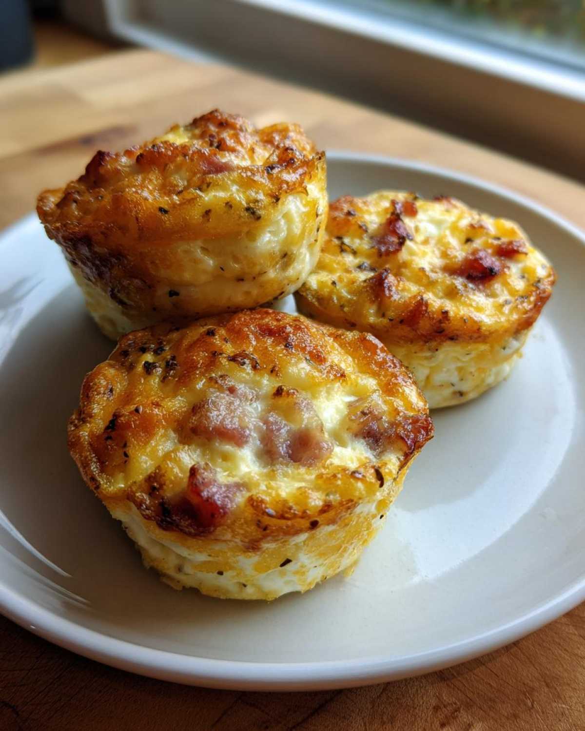 Three golden-brown cottage cheese egg cups starbucks hack style, served on a white plate.