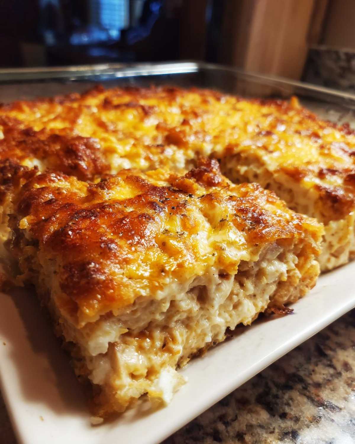 A close-up view of a thick slice of baked Dorito Casserole with a golden, cheesy crust and creamy interior.