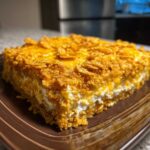 A square slice of creamy Dorito Casserole topped with melted cheese and crunchy crushed Doritos chips.