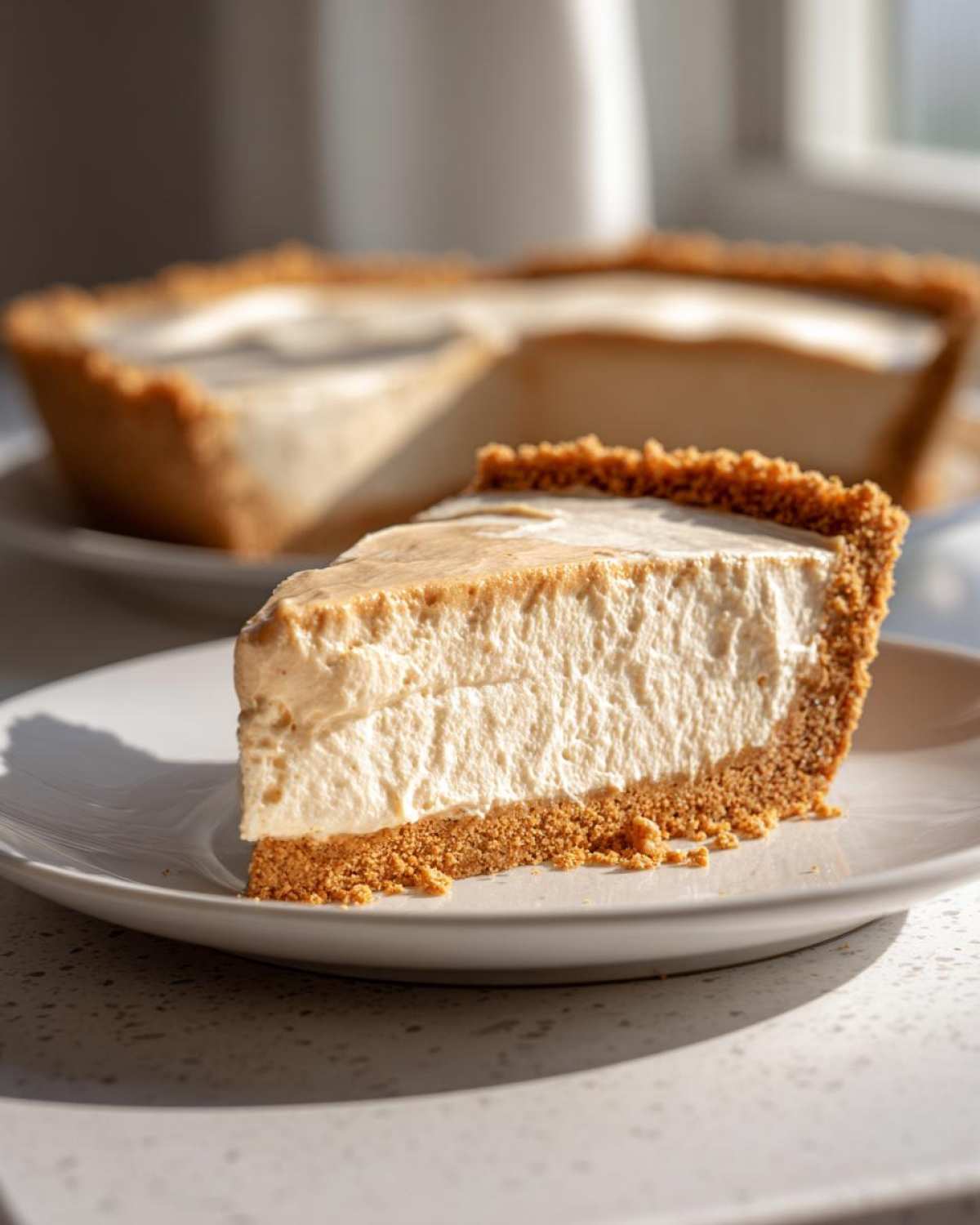 A thick slice of creamy peanut butter pie with a graham cracker crust on a white plate.