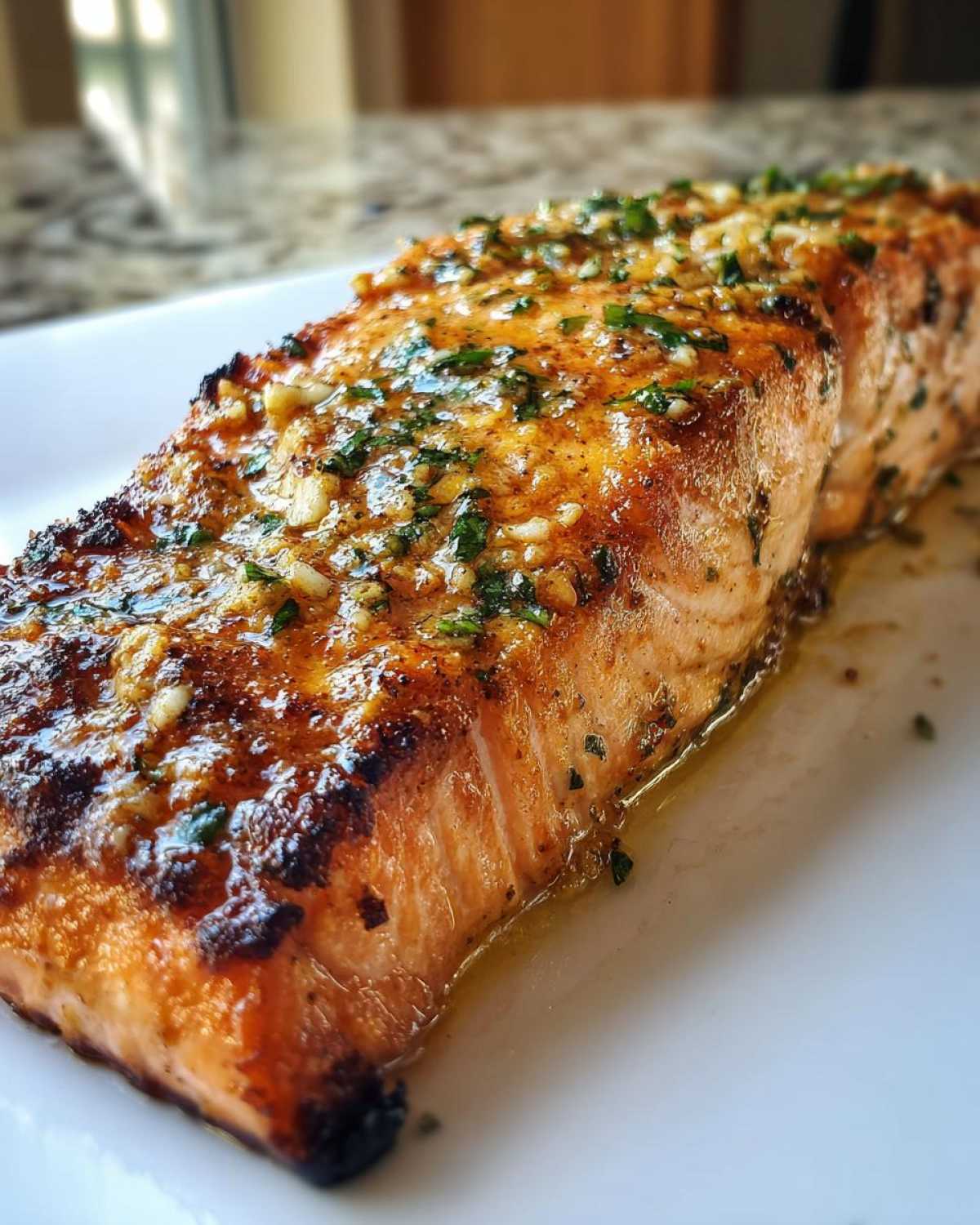 Close-up of a perfectly cooked piece of air fryer salmon with a crispy, golden-brown exterior topped with garlic and herbs.