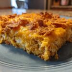 A close-up slice of baked Dorito Casserole showing melted cheese and crunchy topping.
