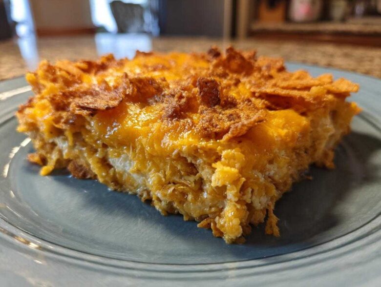 A close-up slice of baked Dorito Casserole showing melted cheese and crunchy topping.