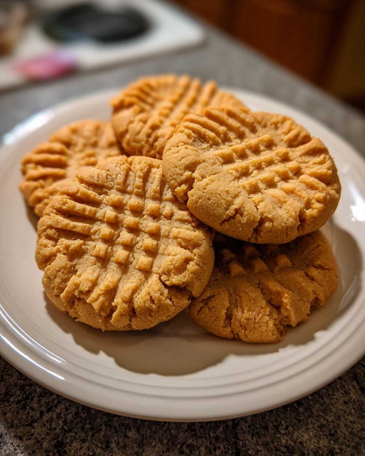 A stack of five golden brown Easy Peanut Butter Cookies with classic criss-cross fork marks on a white plate.