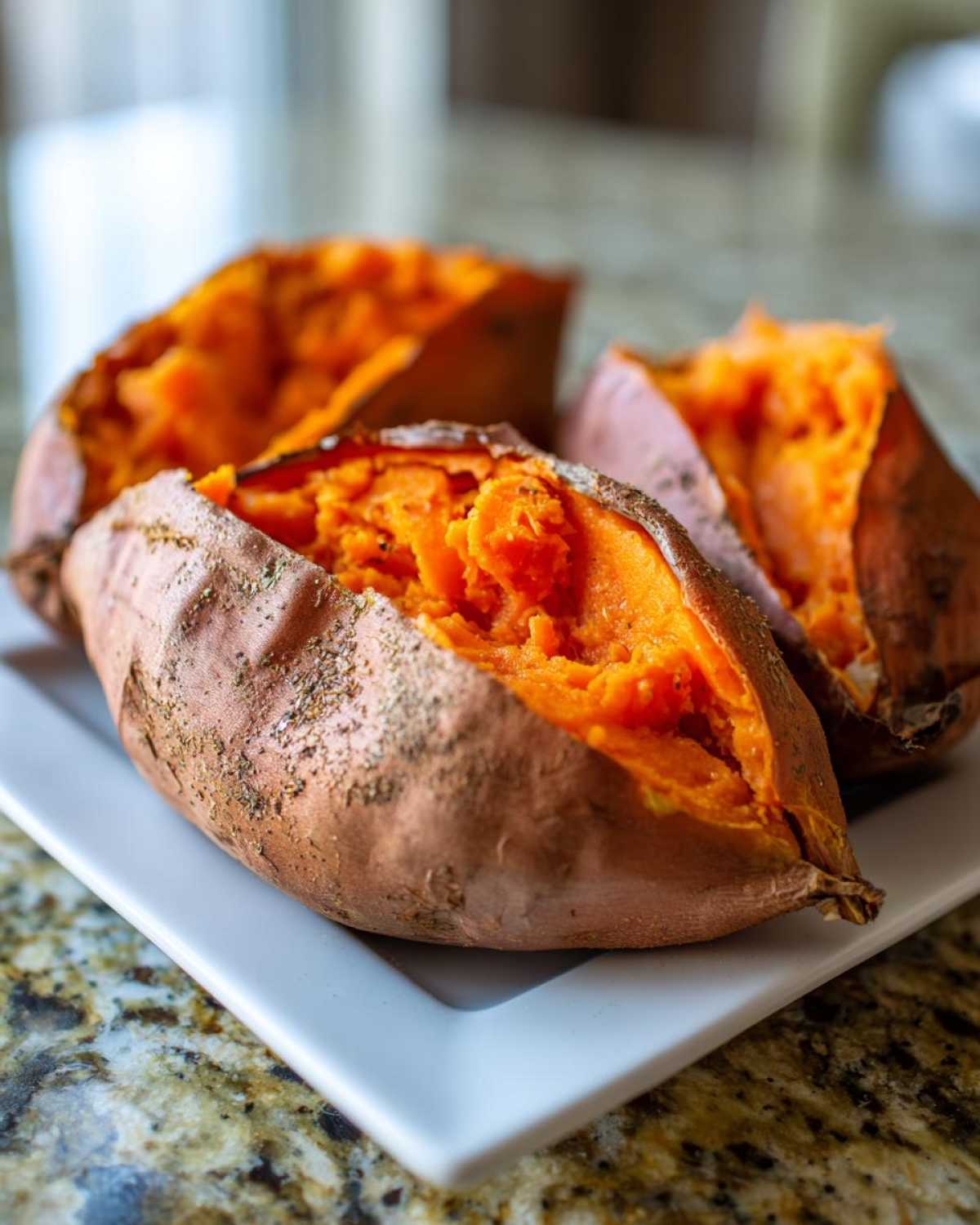 Close-up of fluffy baked sweet potato flesh exposed after being split open, seasoned on the skin.