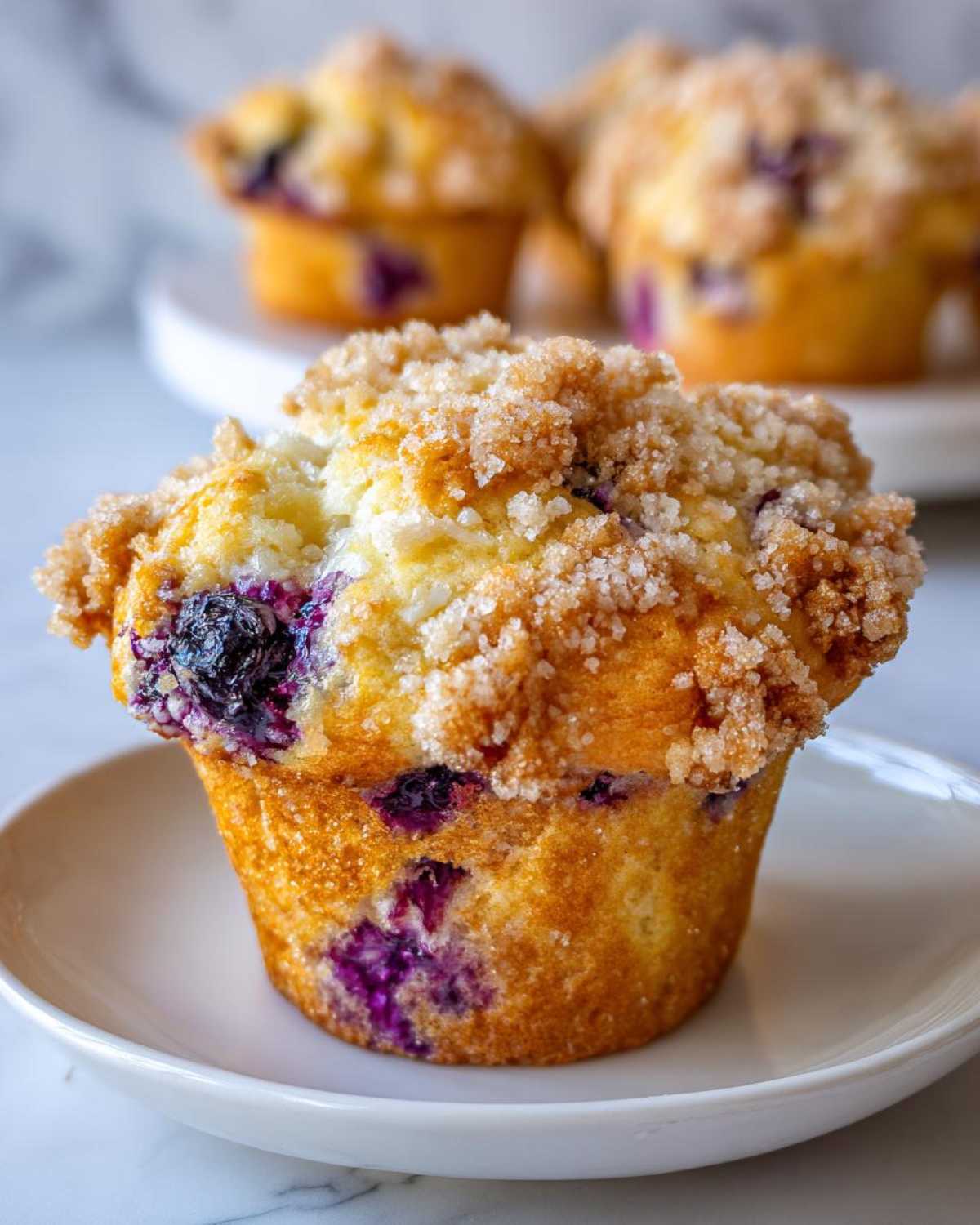 Close-up of a perfectly baked blueberry muffin featuring a golden crumb and sugary streusel topping.