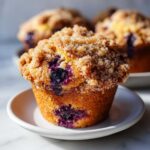 Close-up of a fluffy blueberry muffin topped with sparkling brown sugar streusel.