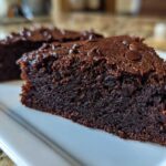 Close-up of a rich, dark slice of fudgy sweet potato brownies topped with chocolate chips.