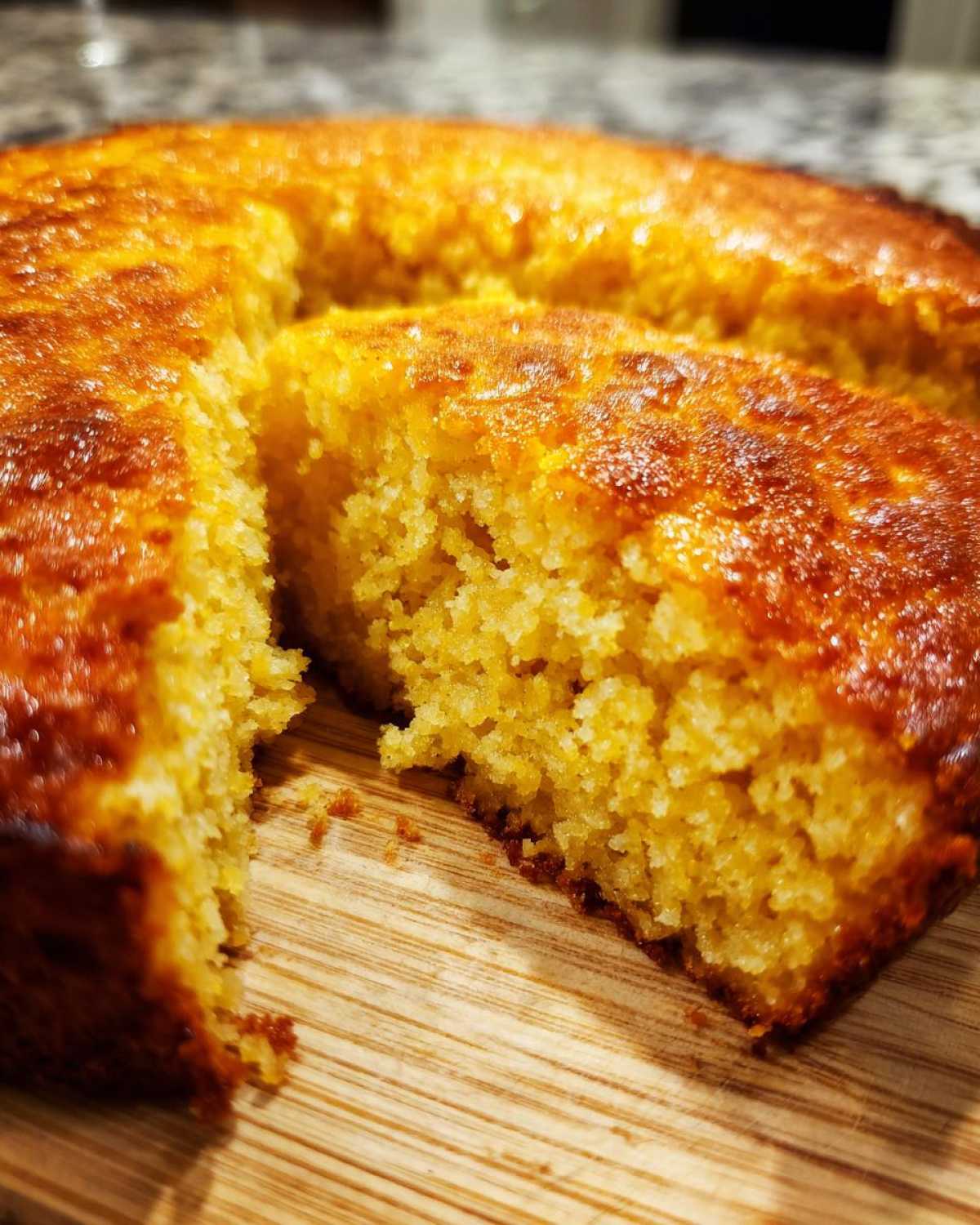 Close-up shot showing the crumb texture of golden skillet cornbread with one slice pulled away.