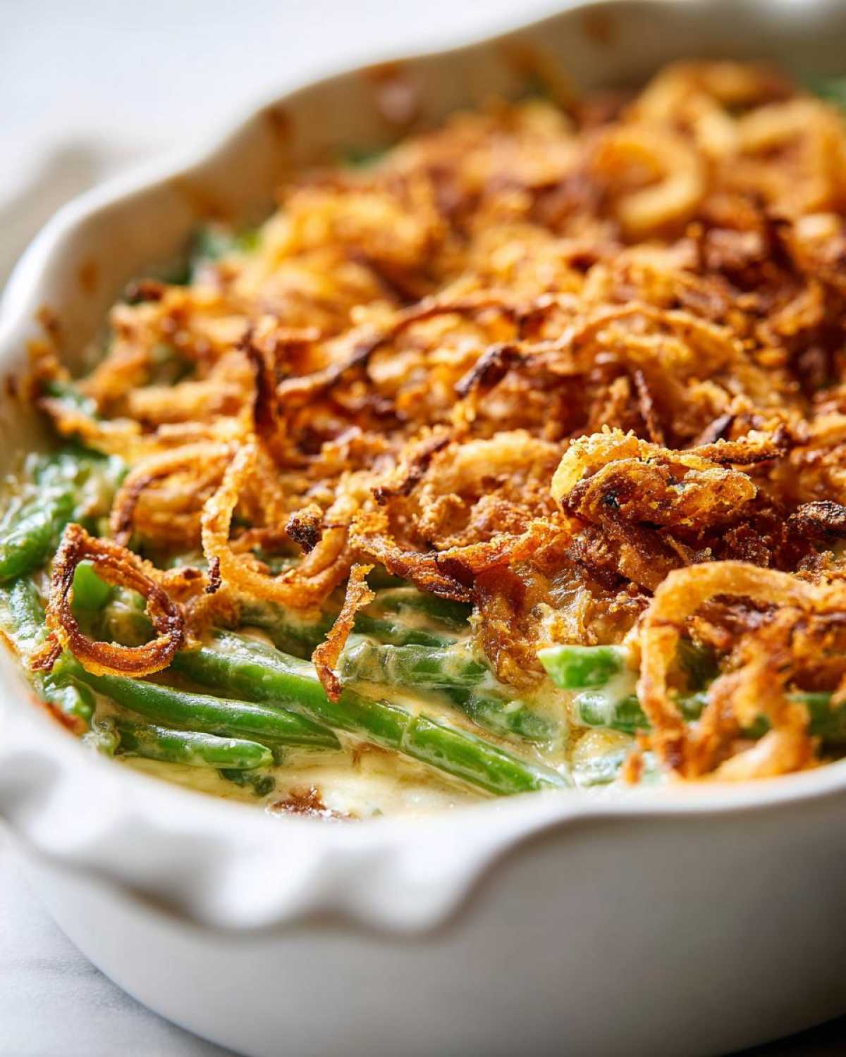 A close-up view of a creamy green bean casserole topped generously with crispy fried onions.