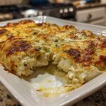 A close-up of baked green chile chicken enchiladas covered in melted, browned cheese in a white baking dish.