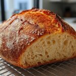 Close-up of a rustic Italian bread loaf, sliced to show the airy crumb and deep golden crust.