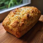 A freshly baked loaf of Italian herb and cheese bread with a golden crust and melted cheese topping.