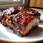 Close-up of thick, glazed, and caramelized pork steak pieces served on a white plate.