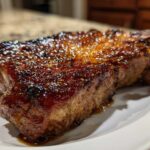 Close-up of a thick, juicy pork steak with a dark, caramelized, and glistening glaze.