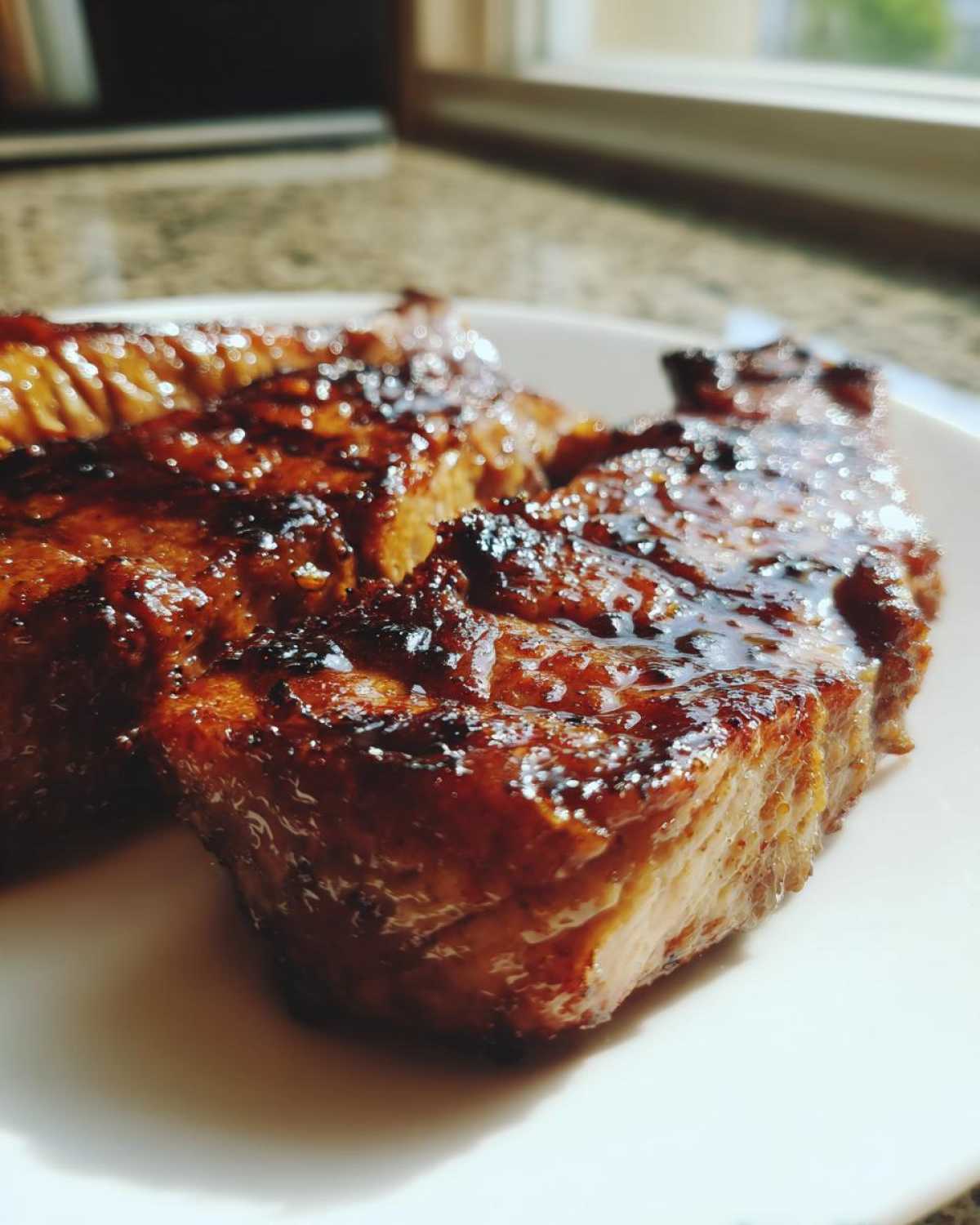 Close-up of a thick, juicy pork steak recipe cut, covered in a dark, shiny glaze.