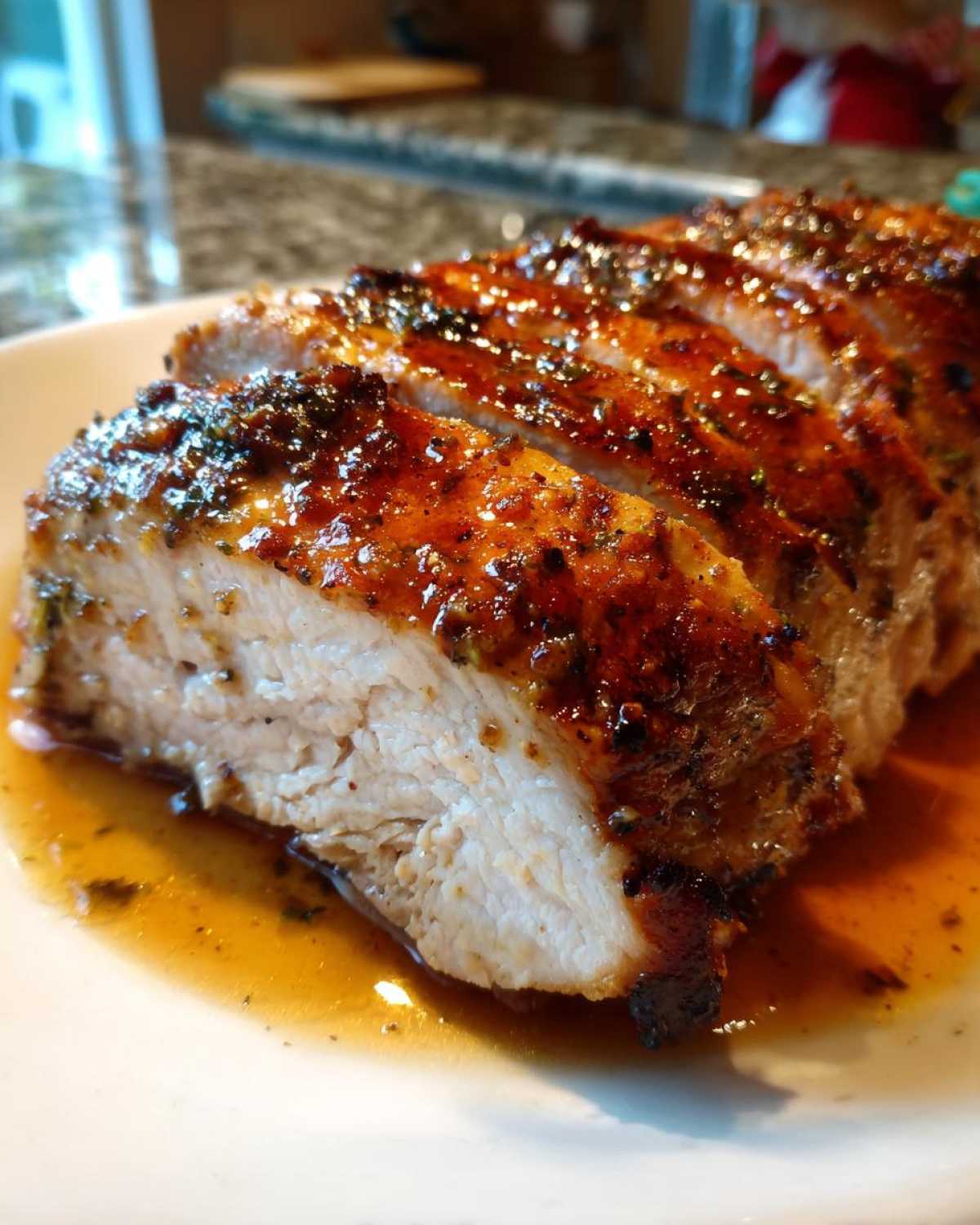 Close-up of perfectly cooked and sliced pork loin roast, showing a juicy interior and a glossy, seasoned crust.