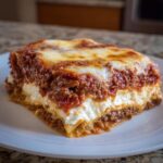 A close-up of a hearty slice of lasagna with cottage cheese, meat sauce, and melted mozzarella cheese topping.