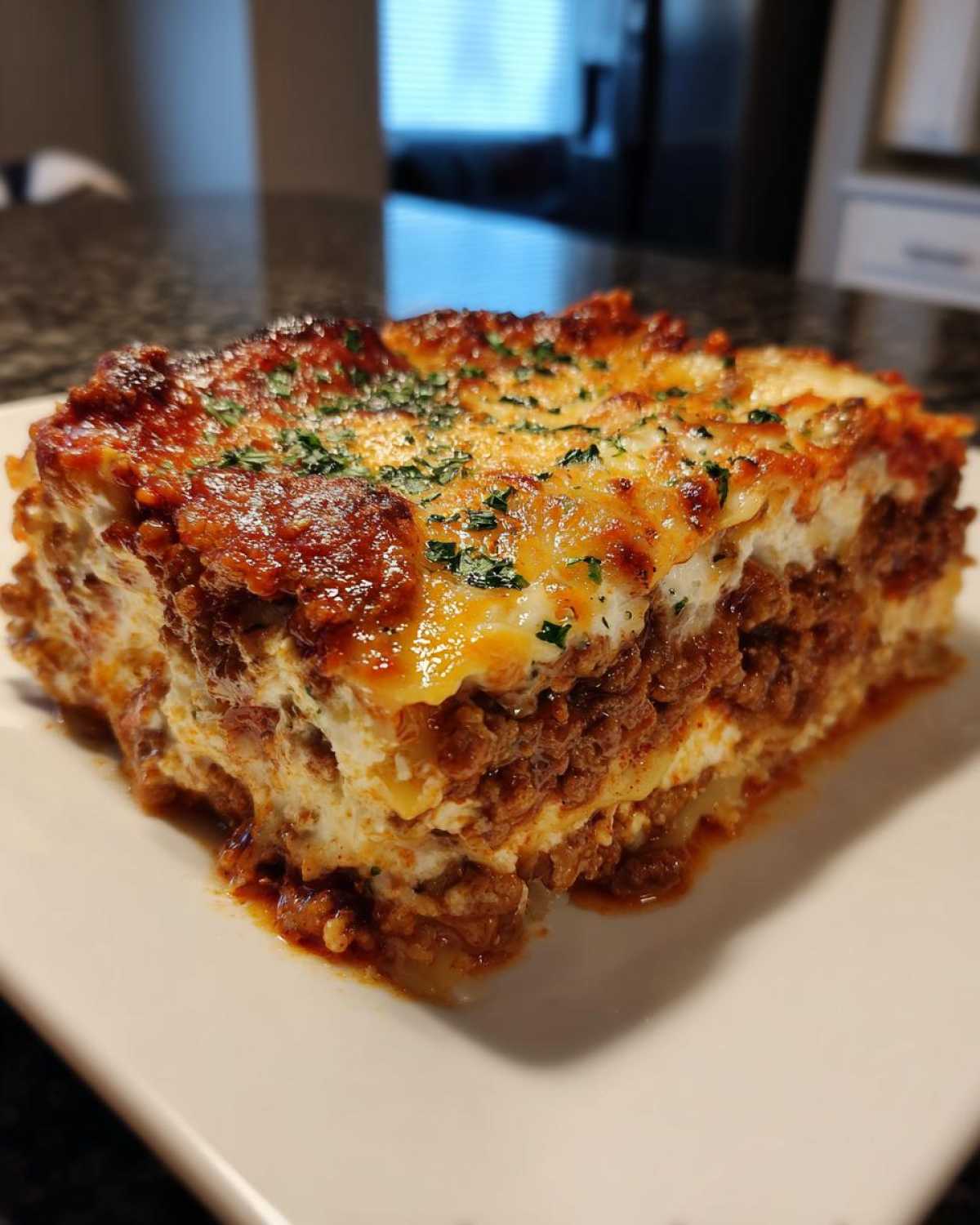 A thick, cheesy slice of Lasagna with Cottage Cheese featuring layers of meat sauce and a browned, herbed top.
