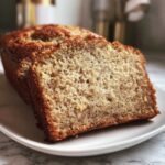 Close-up of a thick slice of moist sugar free banana bread showing the soft crumb texture and brown specks.