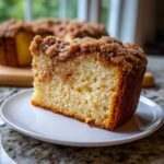 A thick slice of moist coffee cake featuring a rich cinnamon swirl and a generous, sugary streusel topping.