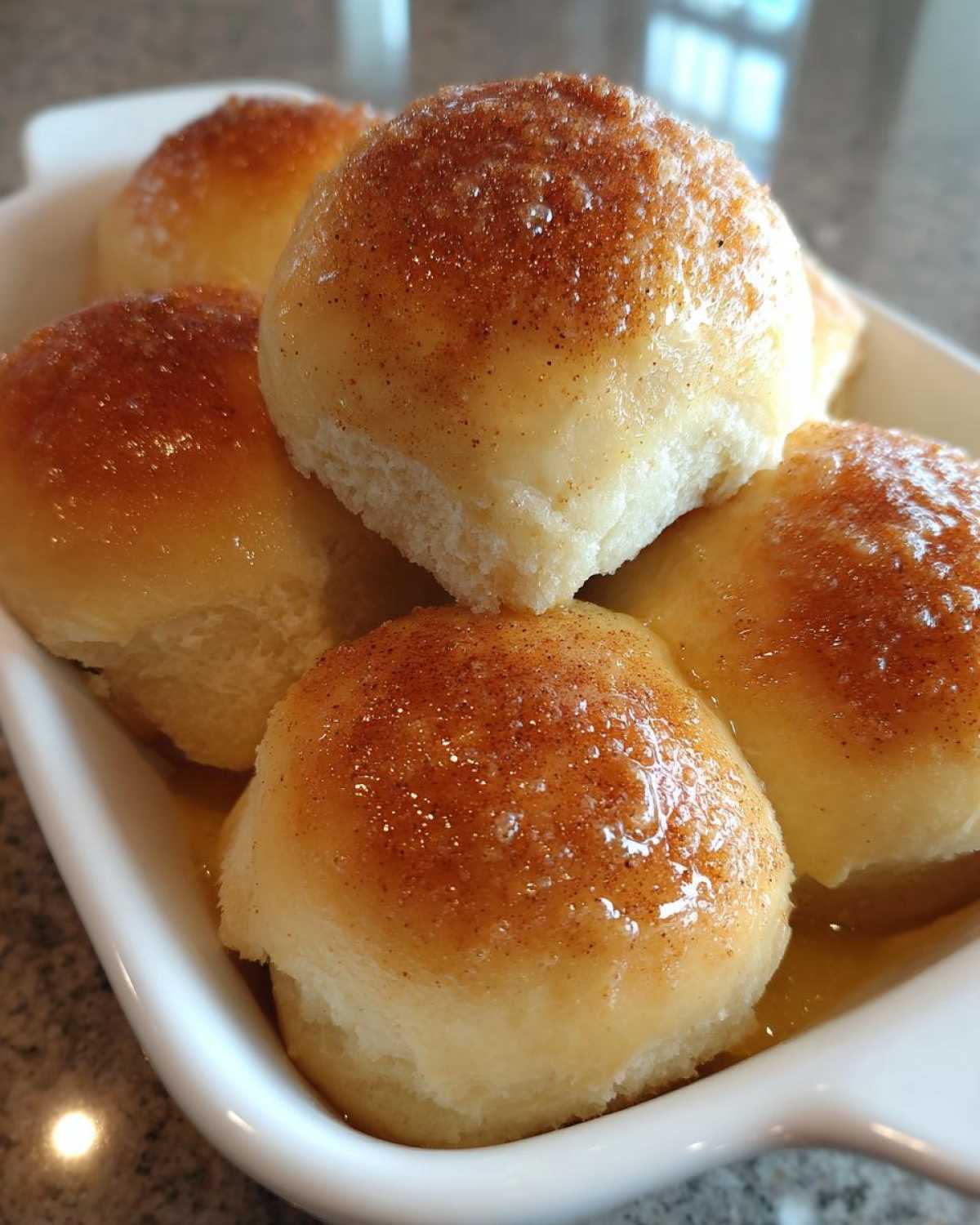 Close-up of freshly baked, soft dinner rolls topped with a shiny glaze and cinnamon.