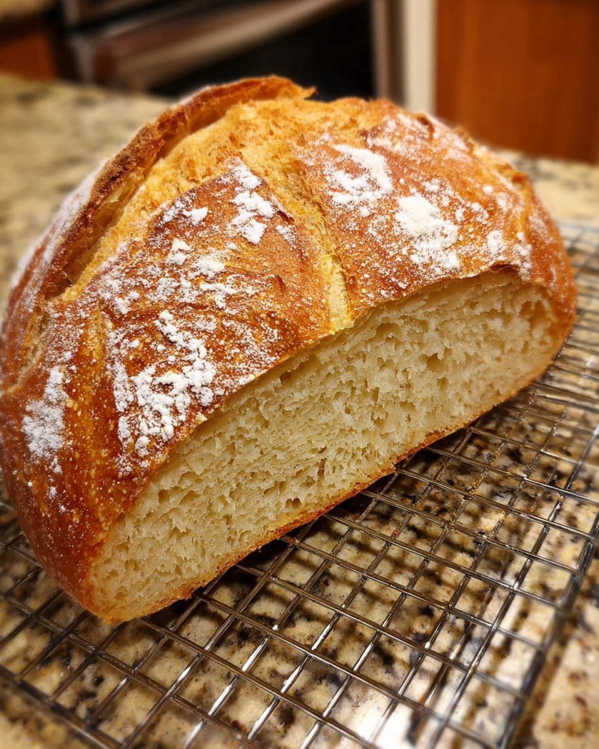 Close-up of a freshly baked loaf of soft French bread, cut open to show the airy crumb, resting on a wire rack.