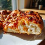 Close-up of a slice showing the airy, fluffy interior crust of sourdough discard pizza dough topped with cheese.