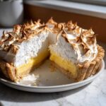 A cross-section view of a stunning lemon meringue pie showing the thick lemon curd and toasted meringue topping.