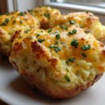 Close-up of golden Twice-baked potatoes stuffed with mashed filling, melted cheddar cheese, and fresh chopped chives.