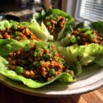 Four servings of amazing chicken lettuce wraps filled with savory ground chicken mixture and topped with green onions.