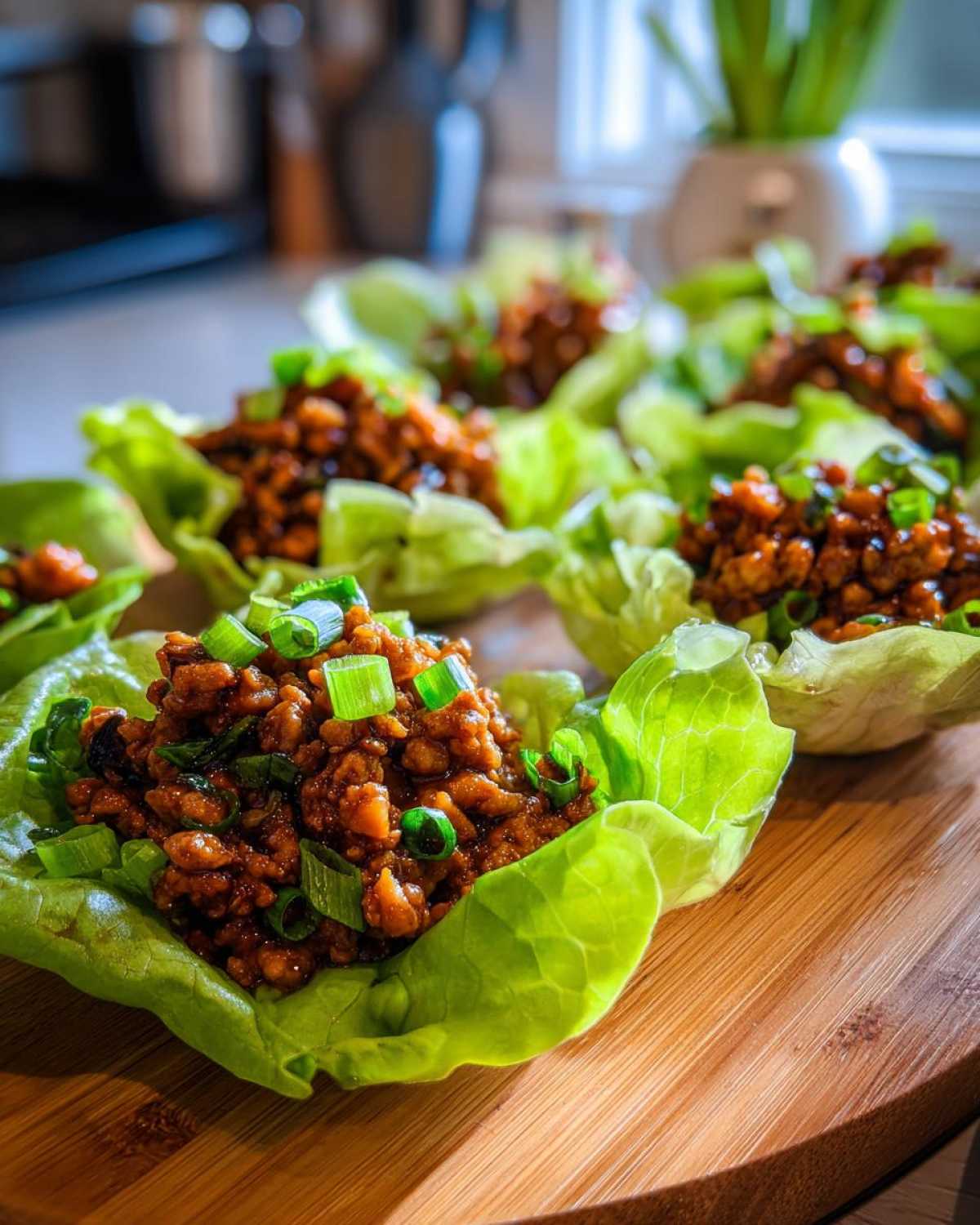 Close-up of savory filling for chicken lettuce wraps served in crisp lettuce cups and topped with green onions.