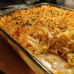 Close-up of a creamy chicken noodle casserole with shredded chicken and a golden, crispy breadcrumb topping.